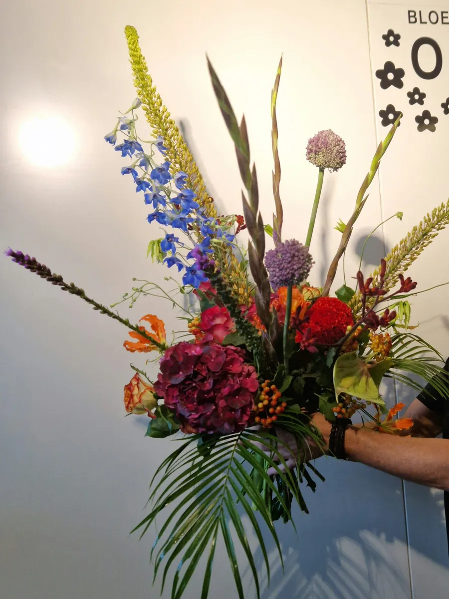 De eigenaar van Bloemenhuis Orchidee met een groot boeket