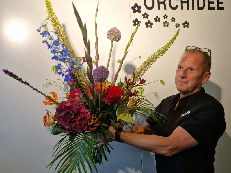 De eigenaar van Bloemenhuis Orchidee met een groot boeket
