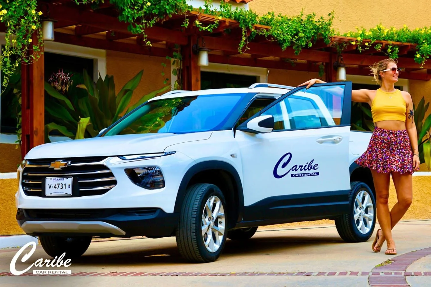 Een witte huurauto van Caribe Car Rental op een binnenplaats op Bonaire